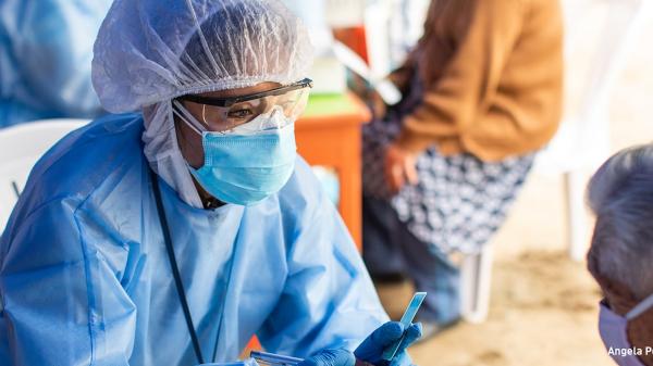 A healthcare provider in personal protective equipment examines a patient